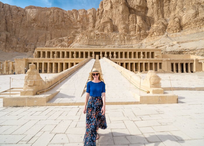 Girl in a dress standing in front of Hatshepsut Temple, showcasing stunning architecture and historical significance.