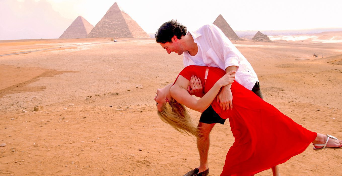 A couple on their honeymoon exploring the pyramids, capturing a romantic moment as foreign tourists.